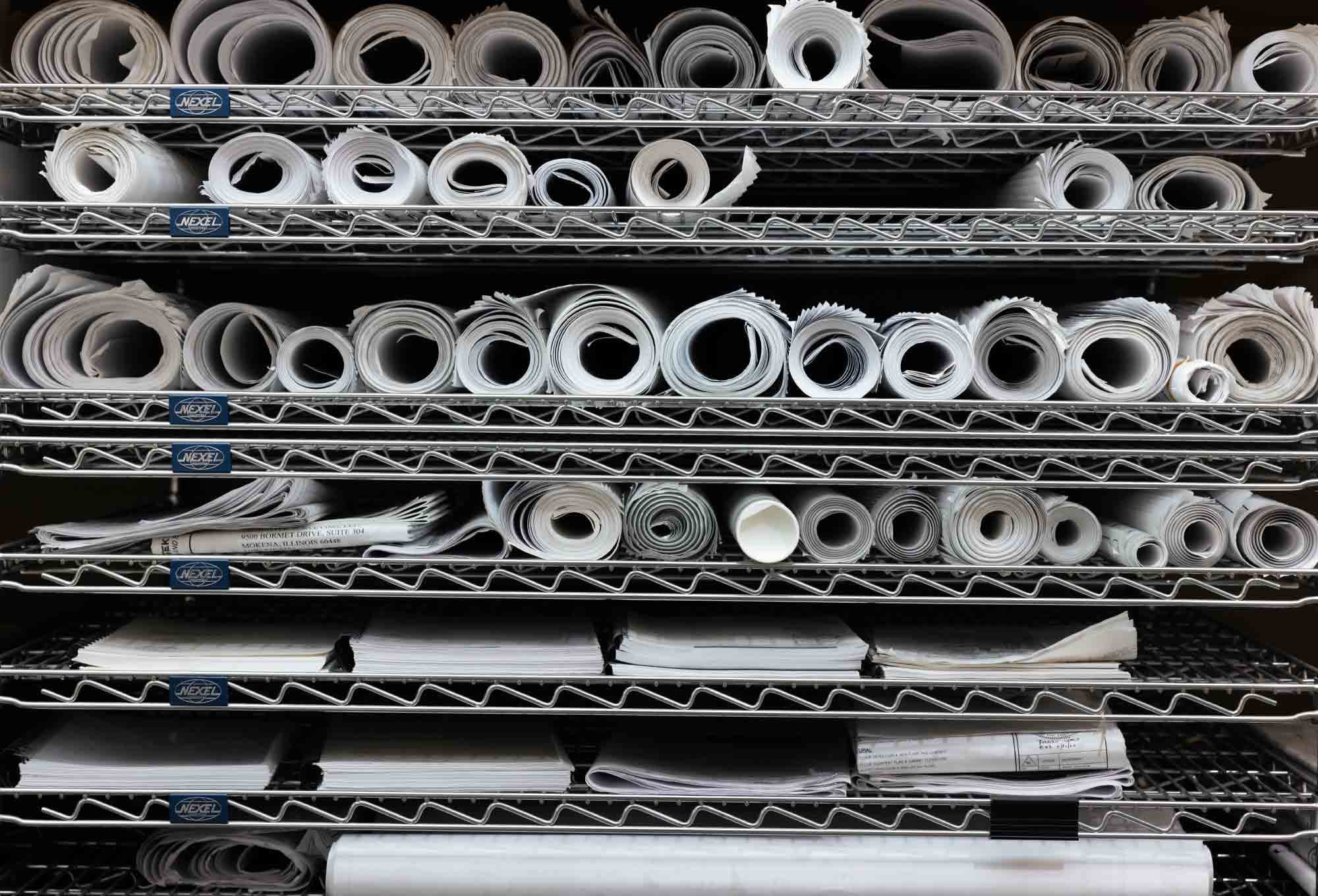Rolls of paper lined up on thin metal shelves