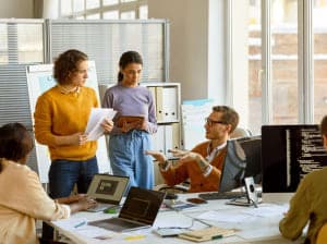 A group of young professionals collaborating around a busy workspace