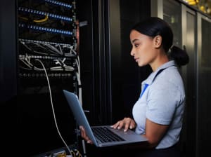 A woman holding a laptop connected to a server