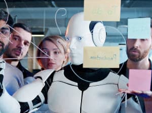 A group of four humans gathered around a robot using a work board