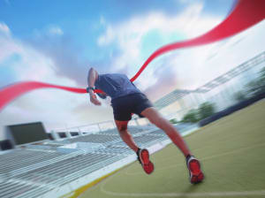 A runner breaking the ribbon at a finish line on a track