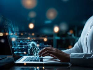 A persons hand hovering over the keyboard of a laptop as a digital hand meets hers, spawning from the screen of the laptop