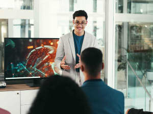 A person standing in front of a room of people - seemingly instructing them