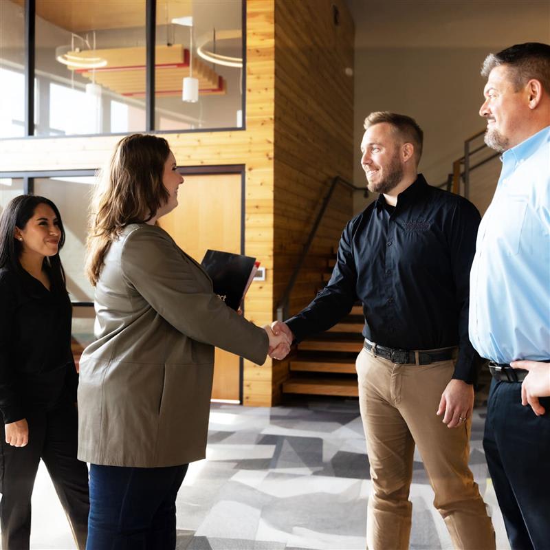 A group of people standing in an entry room shaking hnds.