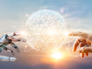 A robot hand and a human hand both point toward the center of the frame where a glowing sphere of golden light swirls together - it sort of resembles a planet.