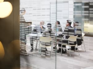 A group of professionals in a conference room pictured through a glass wall
