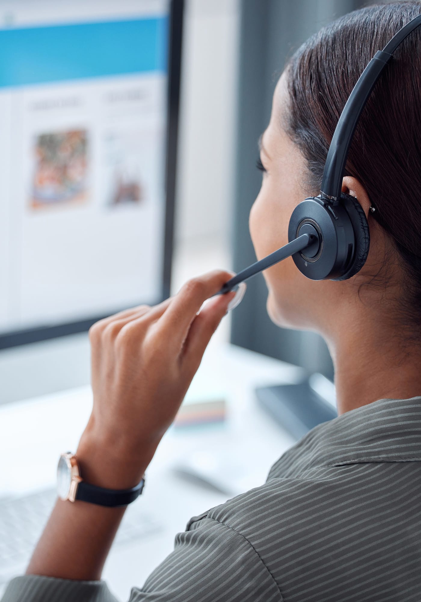 A woman with a headset on in front of a computer taking a customer service call