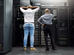 two men working on servers one with hands on head