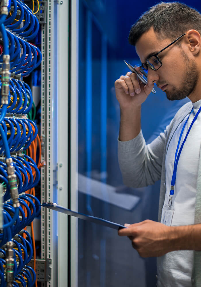 IT worker in front of a server reading something on a tablet
