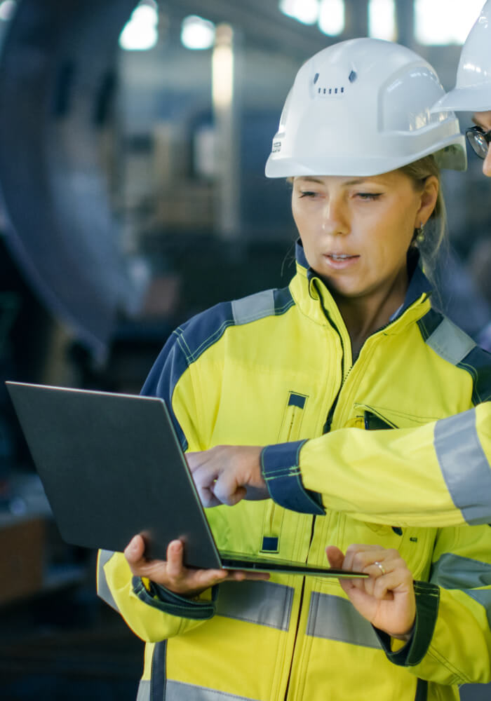 A construction worker doing something on her laptop on site.