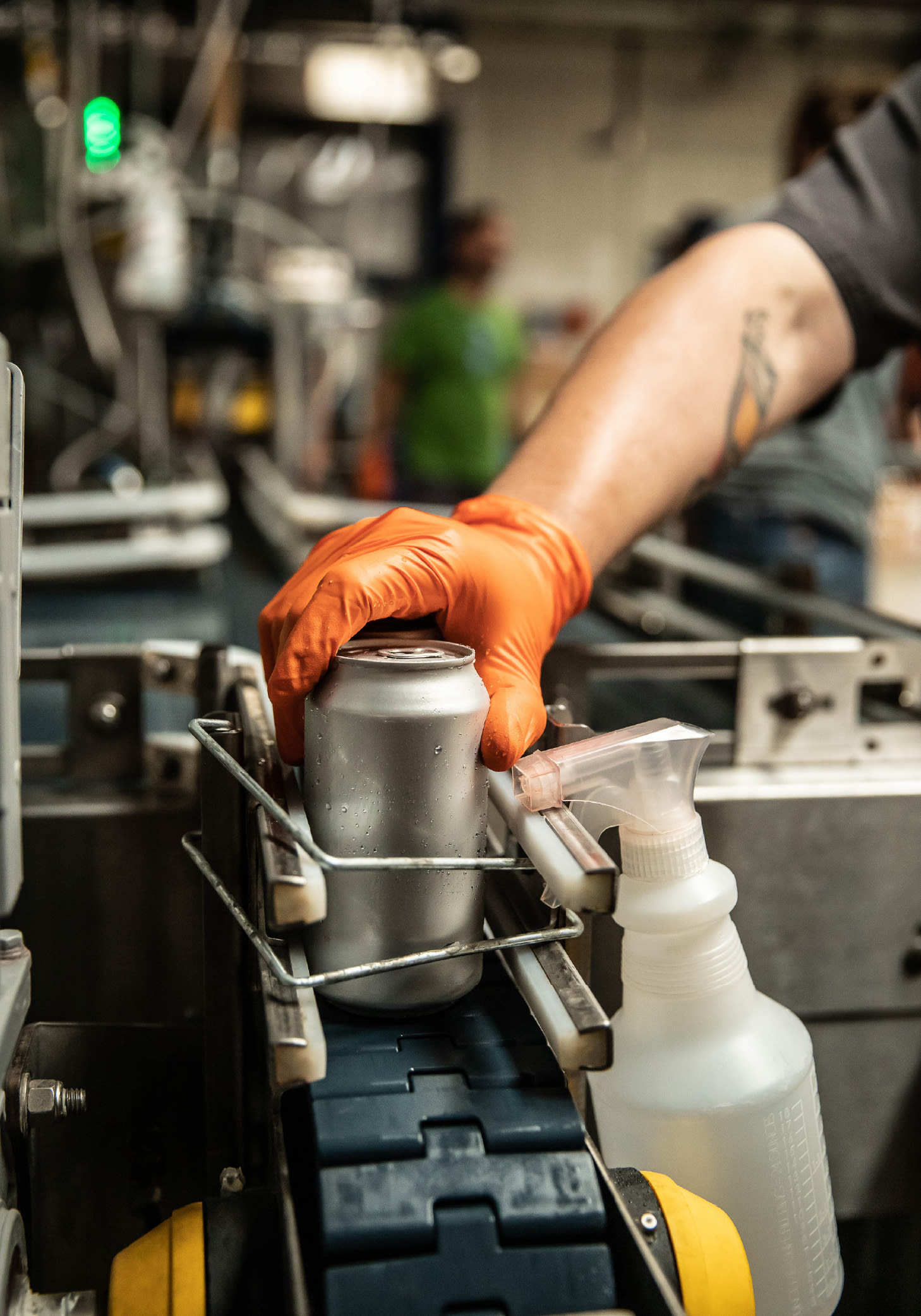 gloved hand on can in manufacturing facility