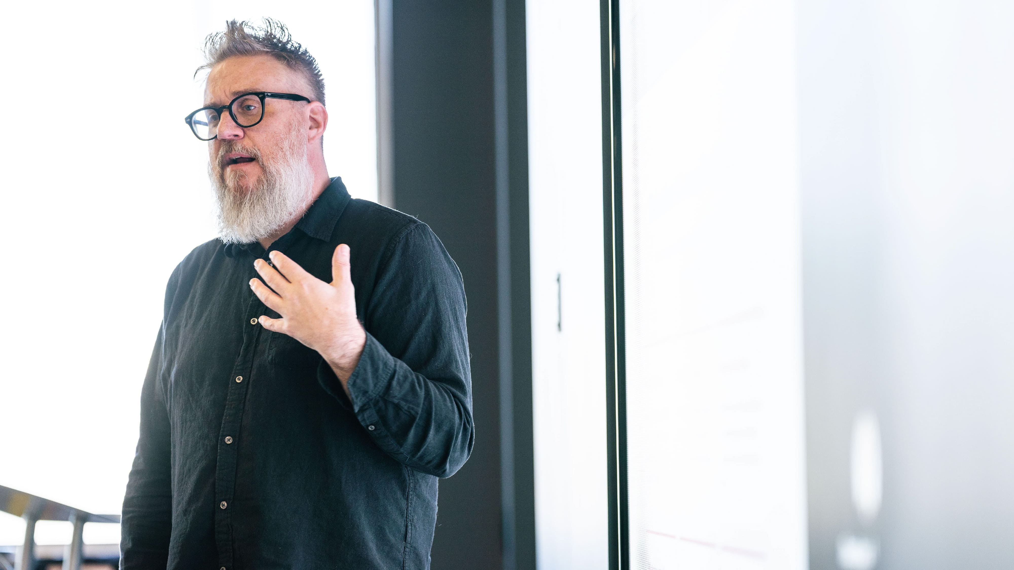 bearded man with glasses standing and talking about AI