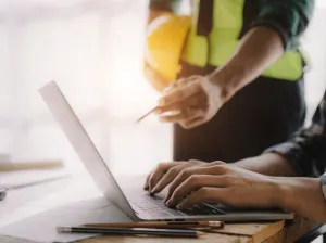 A pair of professionals in the construction industry working on a laptop