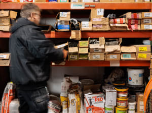 A worker standing at a shelf full of construction hardware