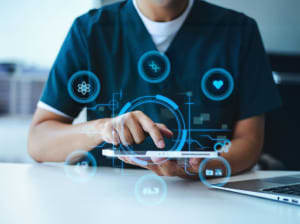 A health practitioner using a smart tablet with digital icons floating in a wheel and spoke pattern around the device