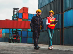 A man and woman dressed for work walking along a shipping yard together