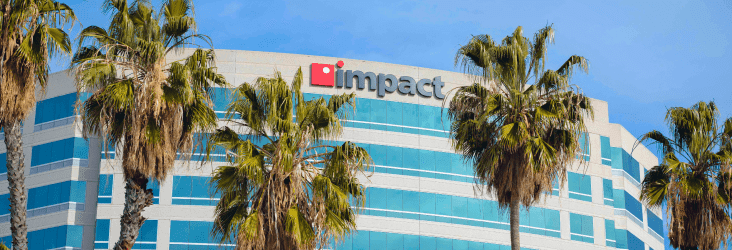 Multi-story building in Anaheim with palm trees in front of it, framing the Impact Networking logo on top of the building