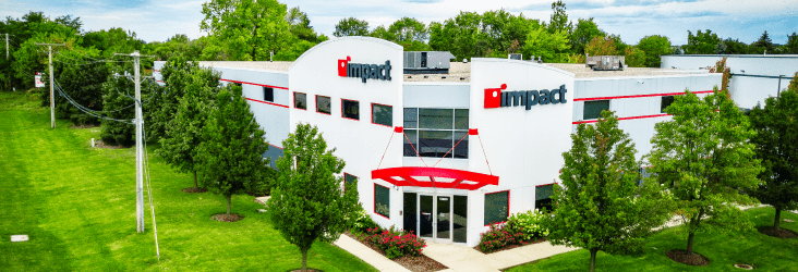 Aerial photo of the Impact Warehouse in Lake Forest, IL - White building framed by trees with the Impact logo on either side of the entrance at the top of the building