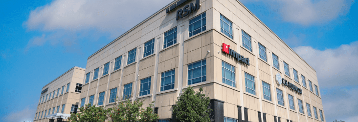 Ground level perspective of a 3 story brown-brick building with the Impact logo visible.