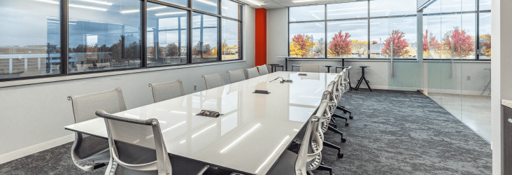 white conference room table surrounded by chairs in a meeting room with big windows