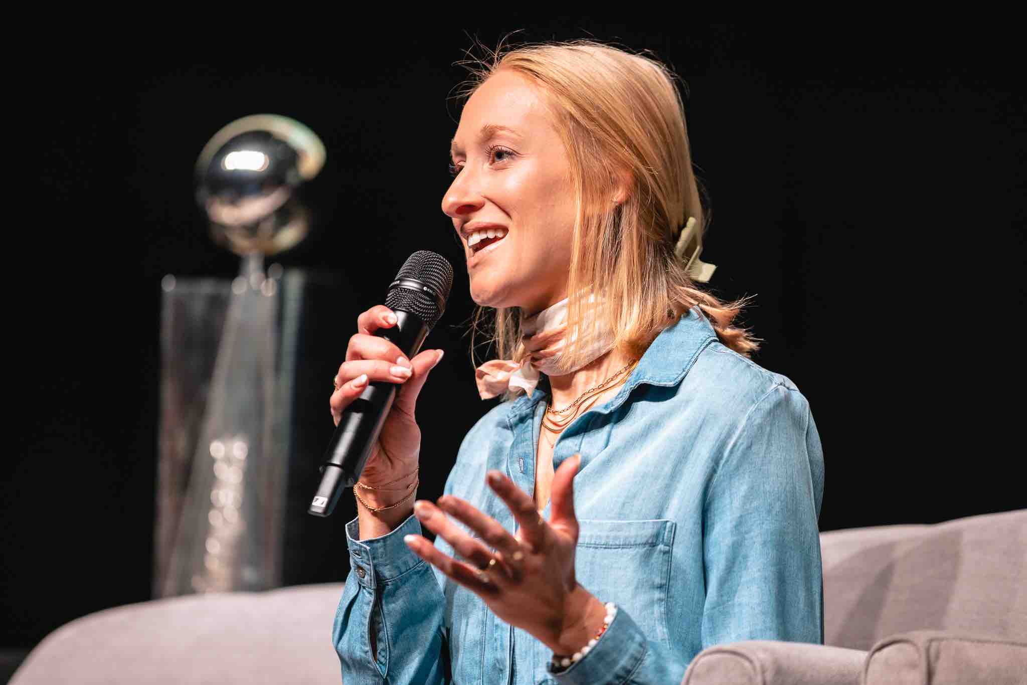woman sitting with a microphone in her hand smiling