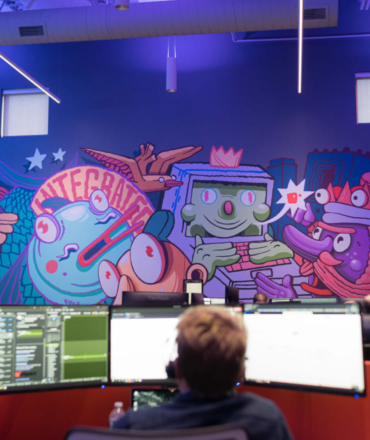 people working on computers with colorful mural in the background