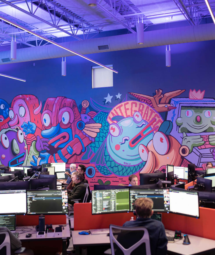 people working on computers in the Impact USO with colorful mural in the background