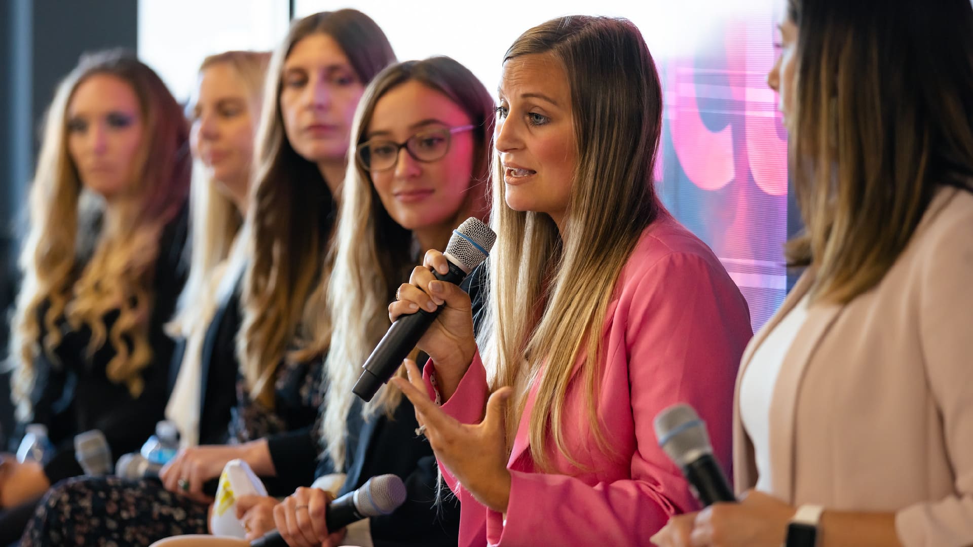 A group of female Impact employees speaking on a panel with microphones