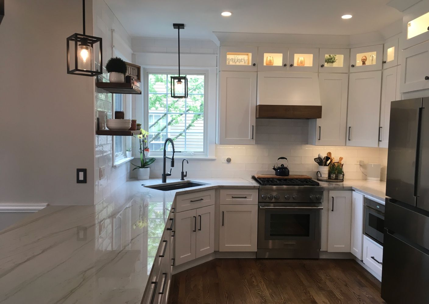 corner kitchen with quartz countertops, white cabinets, and grey tile backsplash