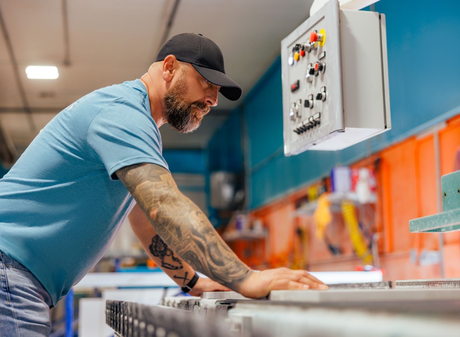 Worker guiding stone slab through sanding machine at Atlantis Fabrication Shop