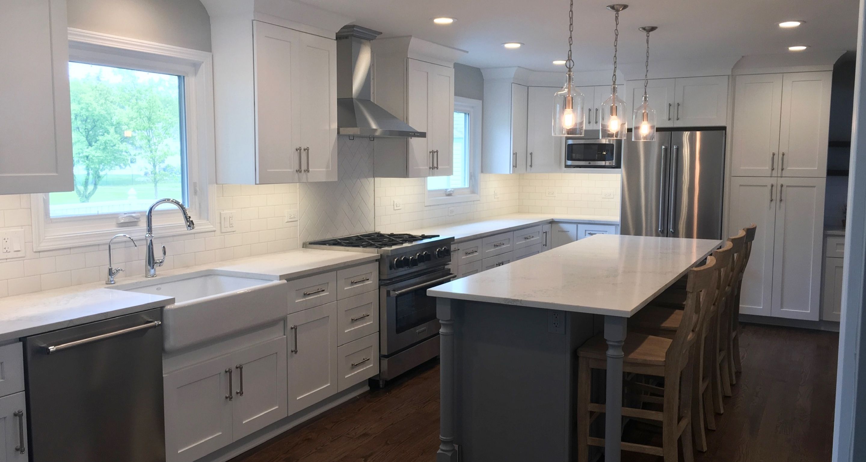Kitchen with stone countertops and island, white cabinets, and white sink