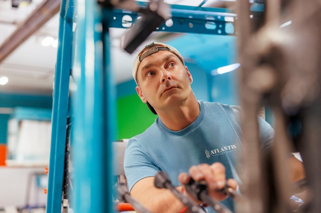 Man using crane to move countertop slab wearing Atlantis t shirt
