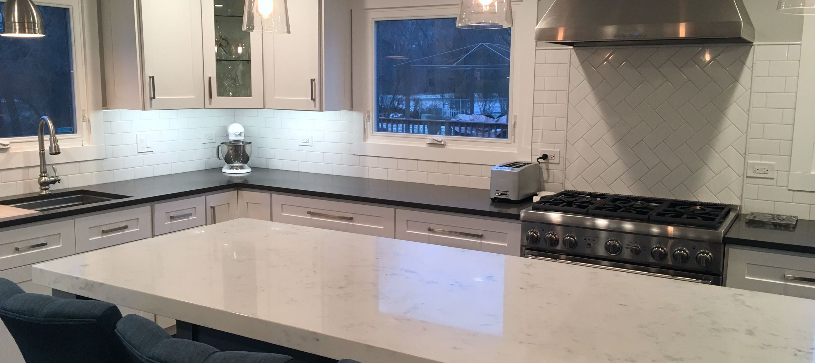 white countertop on a kitchen island with black perimeter countertops and white backsplash