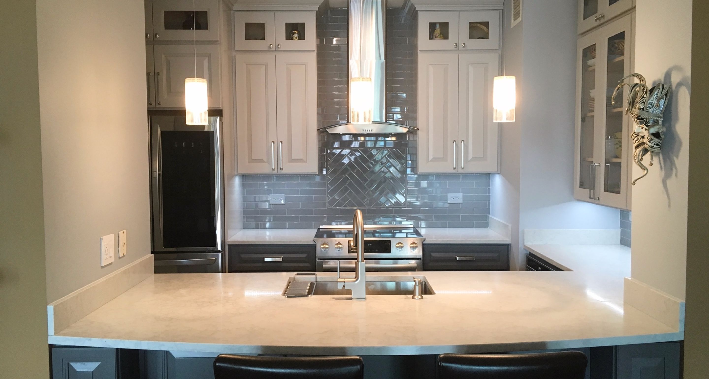 corner kitchen with quartz countertops, white cabinets, and grey tile backsplash