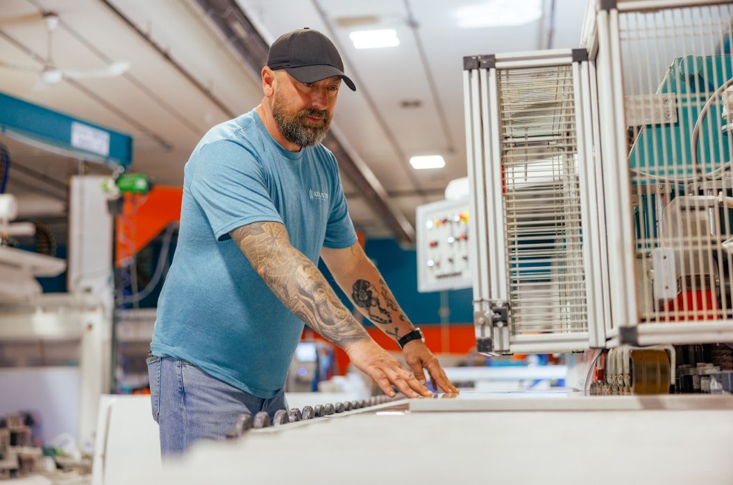 Worker guiding stone slab through sanding machine at Atlantis Fabrication Shop