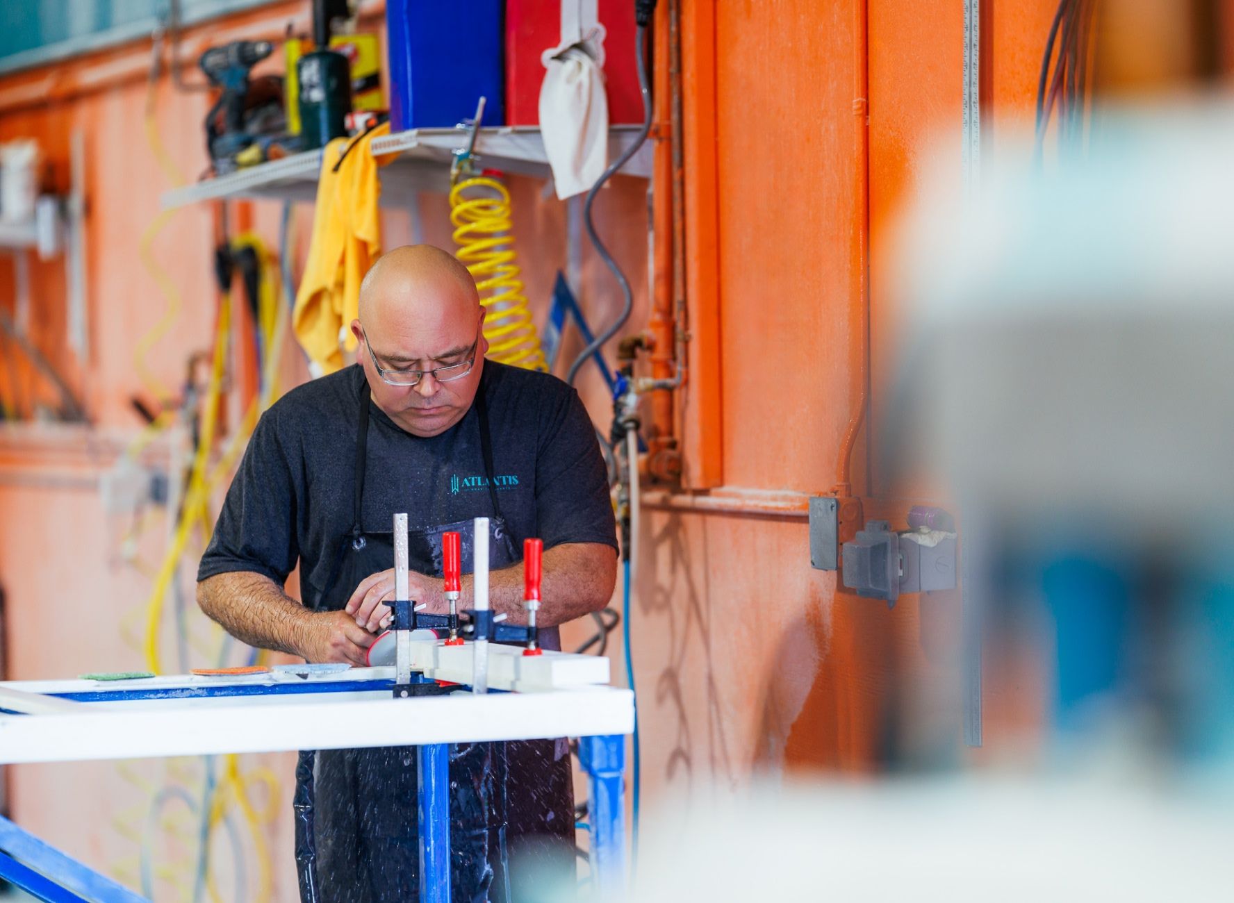 fabrication shop worker in black apron sanding down stone