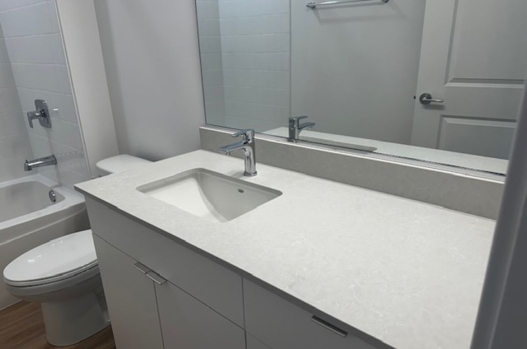 Bathroom vanity with white quartz countertop, and white cabinets at 157+Cicero Apartments