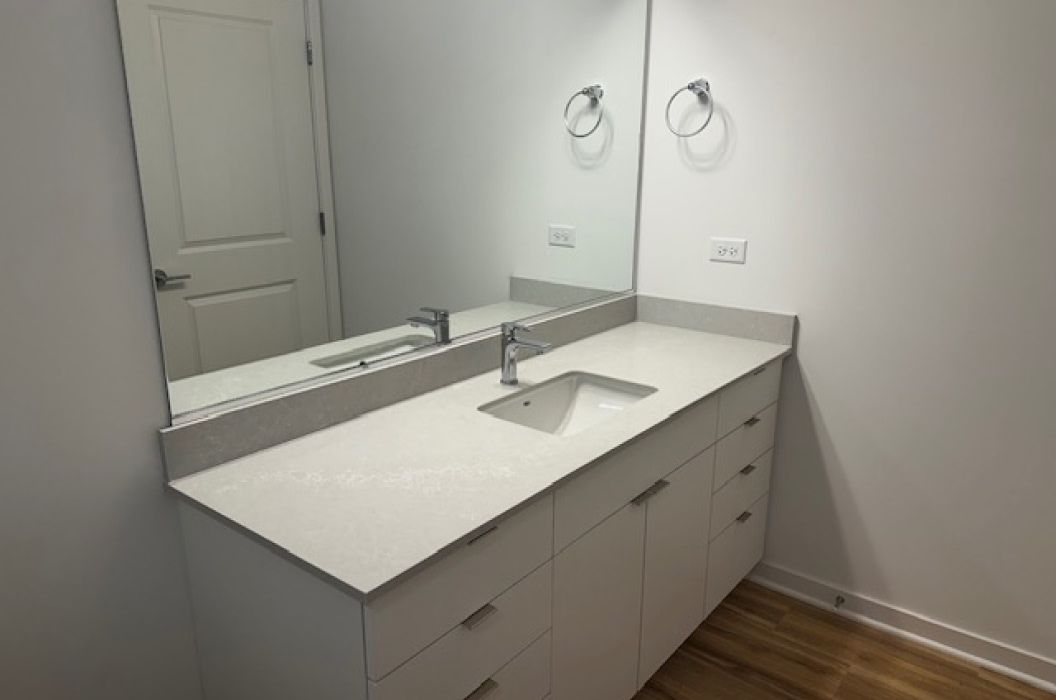 Bathroom vanity with white quartz countertop, and white cabinets at 157+Cicero Apartments