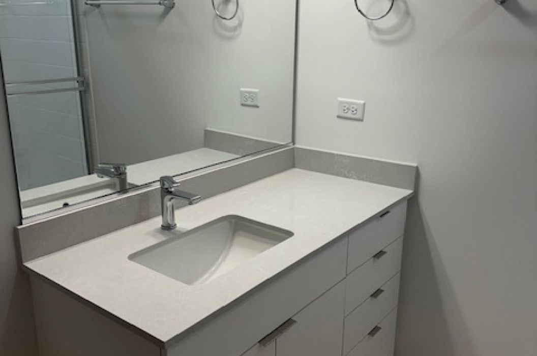 Bathroom vanity with white quartz countertop, and white cabinets at 157+Cicero Apartments